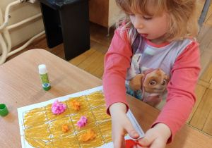 Dziewczynka przykleja kolorowe kuleczki.