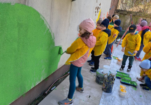 Dzieci wspólnie malują budynek.