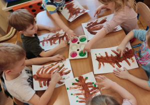 Dzieci robią listki farbą.
