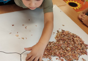 Dzieci przyklejają obierki od kredek.