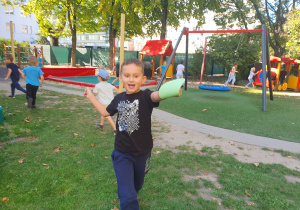 Na zdjęciu chłopiec biegnie z papierową kropką w dłoni znalezioną na placu zabaw