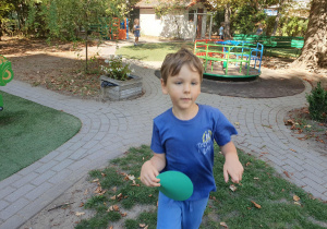 Na zdjęciu chłopiec biegnie z papierową kropką w dłoni znalezioną na placu zabaw
