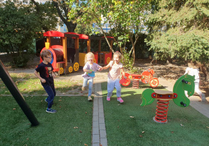 Na zdjęciu dzieci biegną z papierowymi kropkami w dłoni znalezionymi na placu zabaw