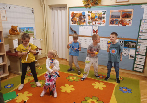 Na zdjęciu widać dzieci, które udają, że grają na instrumentach zrobionych z klocków. Chłopiec ma zrobiony z klocków mikrofon i udaje, że śpiewa.