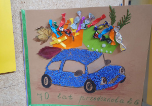 Zdjęcie przedstawia laurkę zrobioną z różnych materiałów z okazji urodzin przedszkola.