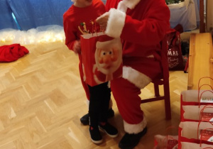 Święty Mikołaj rozdaje dzieciom prezenty.