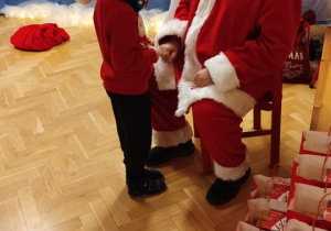Święty Mikołaj rozdaje dzieciom prezenty.
