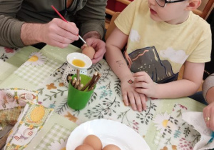 Rodzice ozdabiają jajka wielkanocne.