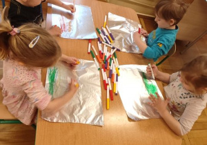 Dzieci malują na folii spożywczej.