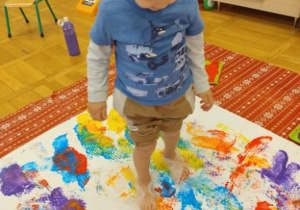Chłopiec maluje stopami.