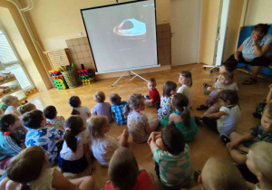 Przedszkolaki oglądają prezentację multimedialną.