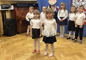 Dzieci stoją na przedszkolnej scenie i prezentują wiersze i piosenki