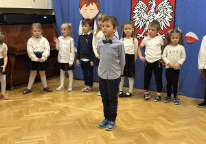 Dzieci stoją na przedszkolnej scenie i prezentują wiersze i piosenki
