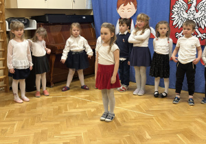 Dzieci stoją na przedszkolnej scenie i prezentują wiersze i piosenki