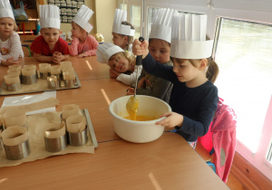 Dzieci mieszają miód do masy na ciasteczka