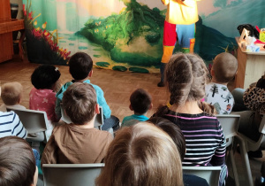 Przedszkolaki oglądają aktorów na scenie.