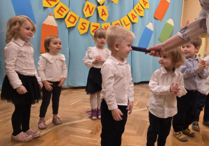 Pasowanie - dzieci stoją w szeregu, pasowanie chłopca