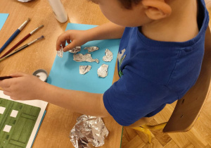 Chłopiec urywa folię aluminiową.