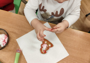 Chłopiec dekoruje pierniczka.