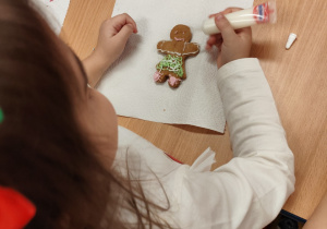 Dziewczynka dekoruje pierniczka.