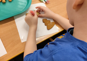 Chłopiec dekoruje pierniczki.