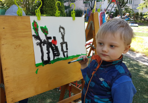 Chłopiec maluje farbami obraz.