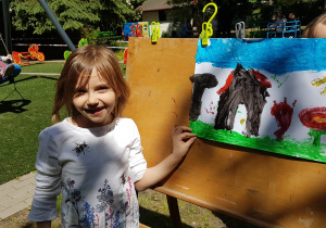 Dziewczynka maluje farbami obraz.