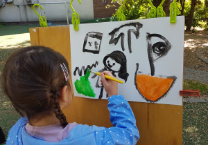 Dziewczynka maluje farbami obraz.