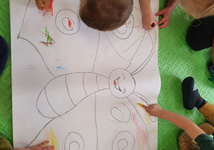 Dzieci kolorują wspólnie znak motyla.