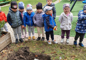 Dzieci sadzą kwiaty w ogrodzie przedszkolnym.