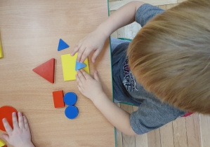 Dziecko układa kompozycję z figur geometrycznych