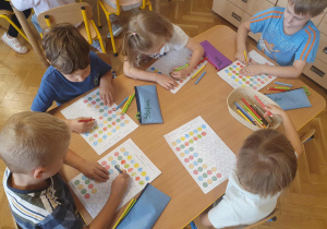 Dzieci na kartach pracy kolorują kropki wg wzoru