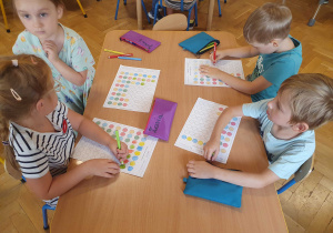 Dzieci na kartach pracy kolorują kropki wg wzoru